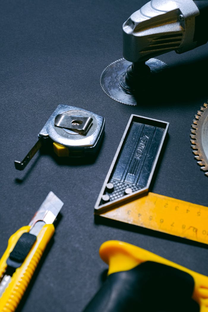journey Assorted hand tools including a tape measure, utility knife, and saw blade on a dark background.