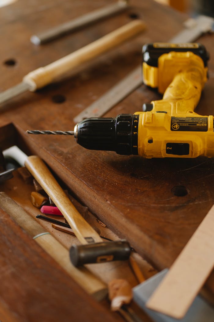 who-we-are From above of contemporary screwdriver with drill near hammer and tools on wooden desk